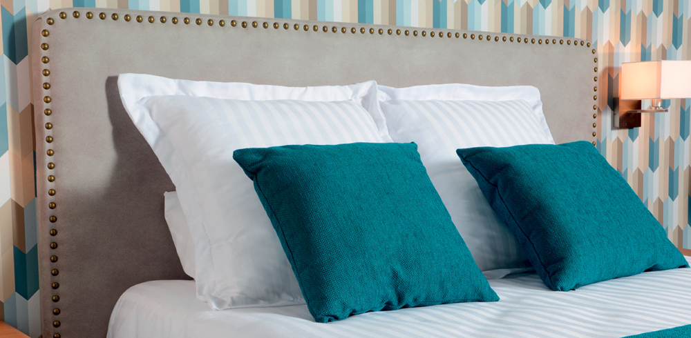 Tête de lit cloutée originale pour hôtel et coussins assortis