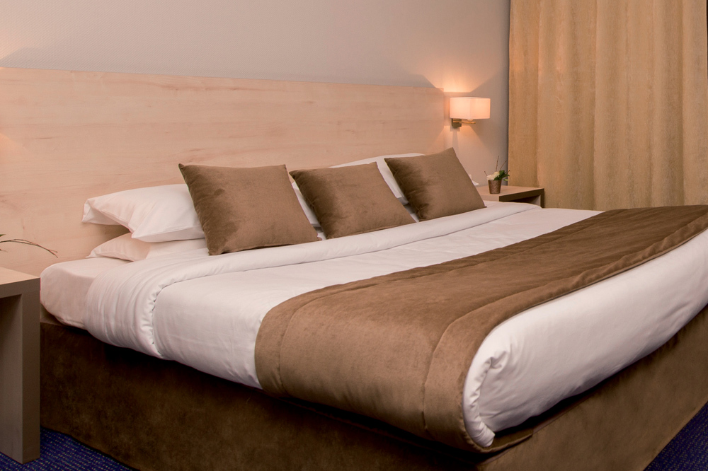 Habillage de lit pour hôtel : chemin de lit, coussins, cache sommier et rideaux